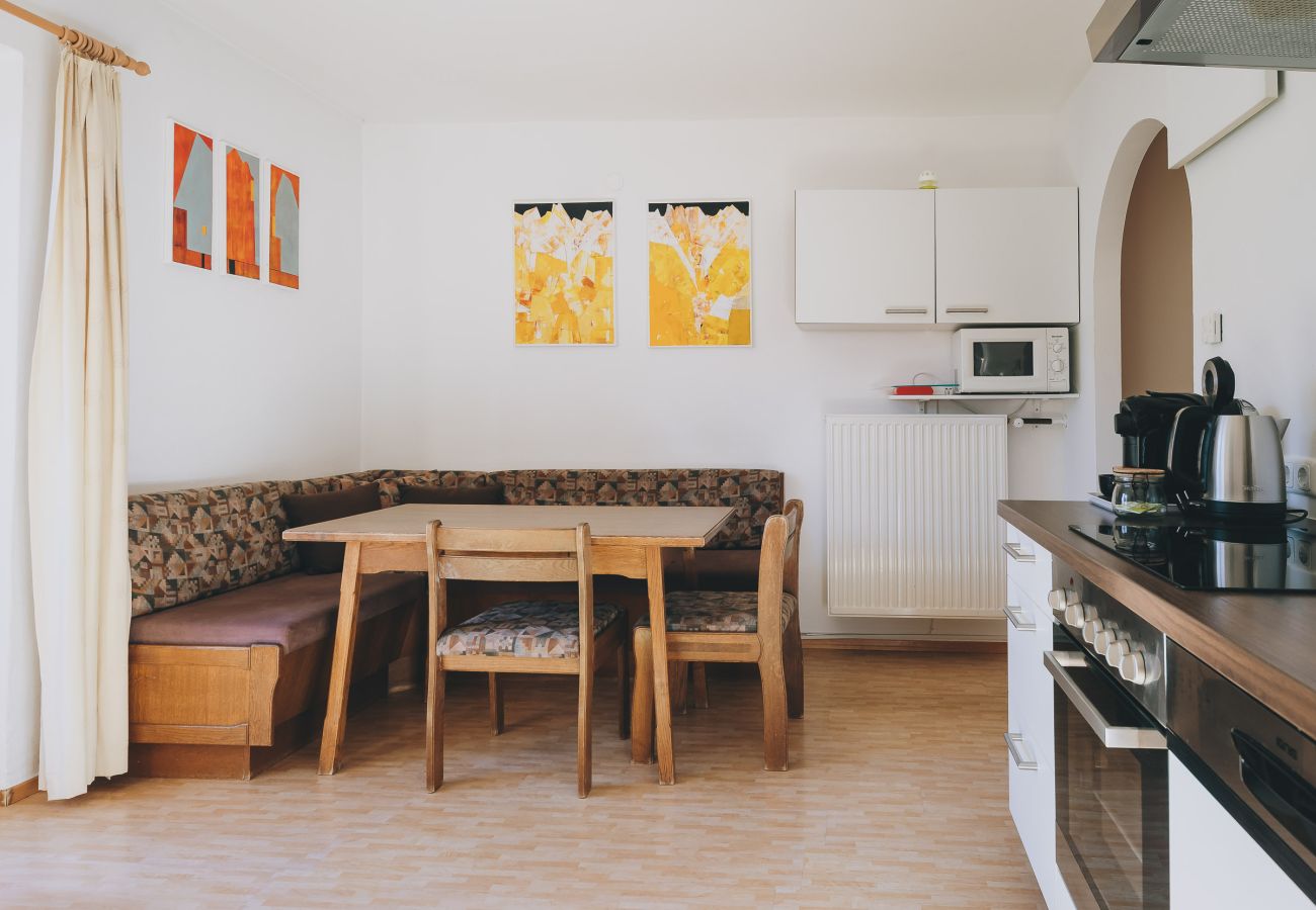 Woonkamer in Apartments Haus Altenberger by we rent. Eettafel en keuken met fornuis en oven.